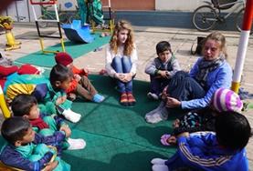 Volunteer Nepal A Care and Community volunteer sits with children in a circle at a placement in Nepal