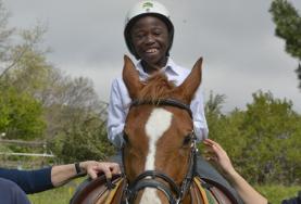 Volunteer South Africa A volunteer supports a disabled boy as he rides his therapy horse at our Equine Therapy placement in South Africa.