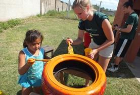 Volunteer Argentina A childcare volunteer and a local child work together to paint a tyre to be repurposed for a playground in Argentina.