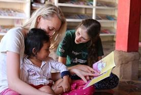 Volunteer Care Volunteers read and interact with a child on a Care Placement in Cambodia