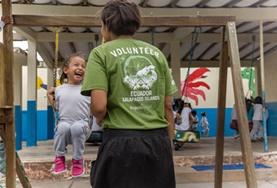 Volunteer Ecuador A childcare volunteer pushes a young girl on a swing in a playground in Ecuador.