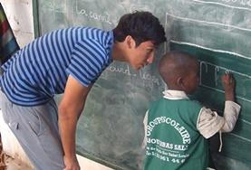 Volunteer Senegal A childcare volunteer teaches a local child in Senegal how to write using a blackboard.