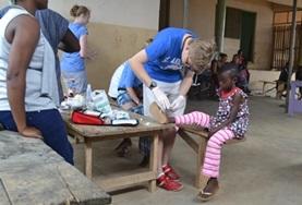 Volunteer Ghana A Medicine volunteer in Ghana assists with cleaning a child's wound during a healthcare outreach over the Christmas period.