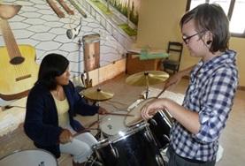 Volunteer Creative & Performing Arts A volunteer and student interacts with muscial instruments
