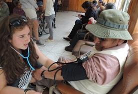 Volunteer Medical Electives Volunteer monitors vital signs of a patient on a medical outreach