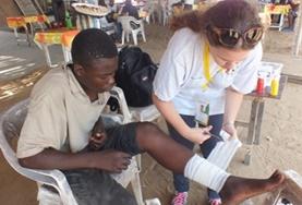 Volunteer Togo An intern completing her Nursing Elective in Togo assists with bandaging a child's wound during a medical outreach.
