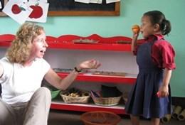Volunteer Nepal An older volunteer teaches a local school child in Nepal about English words through a practical exercise.