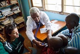 Volunteer Medicine & Healthcare A volunteer and doctor inspect children