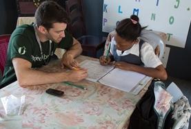 Volunteer Belize A professional Basic Skills Teacher volunteering in Belize conducts a one-on-one literacy lesson with a school child.