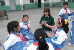 Volunteer China A high school volunteer sits in a playground in China with local children, playing an educational game with them.