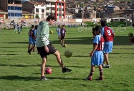 Volunteer Peru A Sports volunteer teaches school children his technique for kicking a football on our Multi-sports project in Peru.