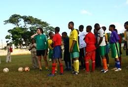 Volunteer Jamaica A volunteer coaches students through a football drill during a school sports lesson in Jamaica.