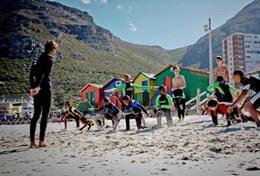 Volunteer Sports A volunteer works with local children on their surfing technique during a lesson in South Africa.