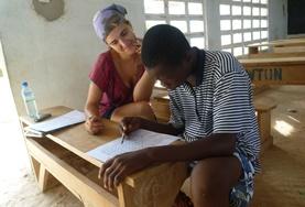 Volunteer Teaching A volunteer French teacher assists a students with his work at a placement in Togo
