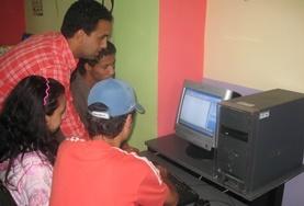 Volunteer Morocco School students and volunteers gather around a computer in preparation for a lesson on our volunteer Teach IT project in Morocco.