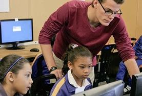 Volunteer South Africa A Teach IT volunteer demonstrates important computer skills to a young girl at a school in South Africa.